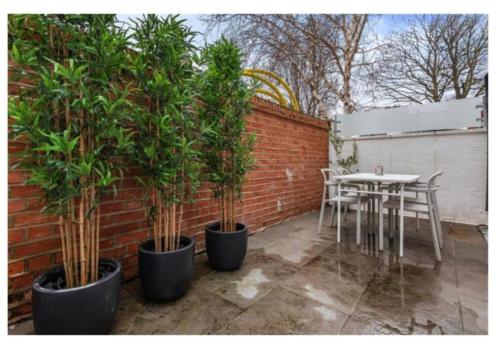 a patio with a table and trees and a brick wall at Richmond Maisonette 3 bed, 2 bath & garden terrace in Richmond