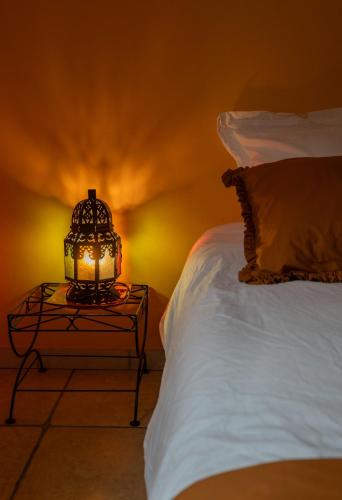 a lamp on a table next to a bed at La Petite Maison Gannat in Gannat