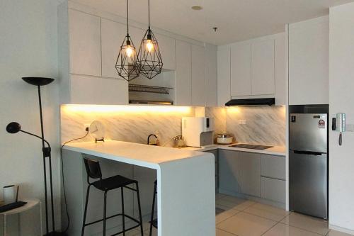 a white kitchen with a counter and a refrigerator at Sunway Onsen Suites - Theme Park Tambun Ipoh by Ryokan Management in Tambun
