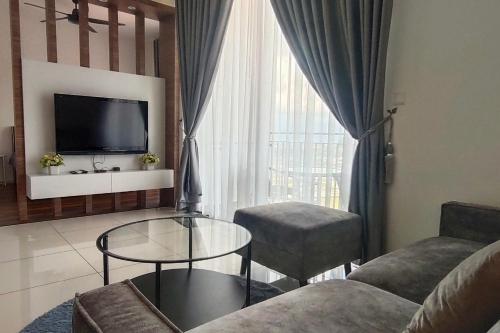 a living room with a couch and a table and a tv at Sunway Onsen Suites - Theme Park Tambun Ipoh by Ryokan Management in Tambun