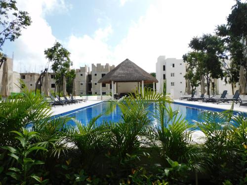 a large swimming pool with chairs and a gazebo at CARRIBEAN DELUXE Apartment in Playa del Carmen