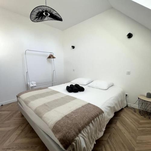 a white bedroom with a bed with a pair of shoes on it at Duplex design - 6 personnes - Charleville-Mézières in Charleville-Mézières