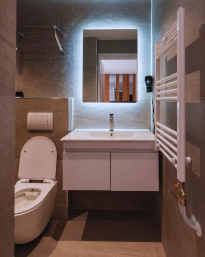 a bathroom with a sink and a toilet and a mirror at Hotel SOLO 127 in Prizren