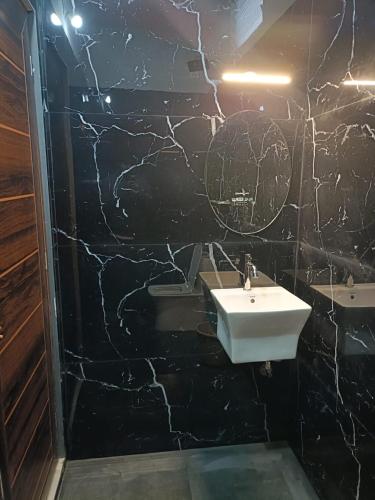 a bathroom with a sink and a black marble wall at Coorg wildstone Homestay in Madikeri