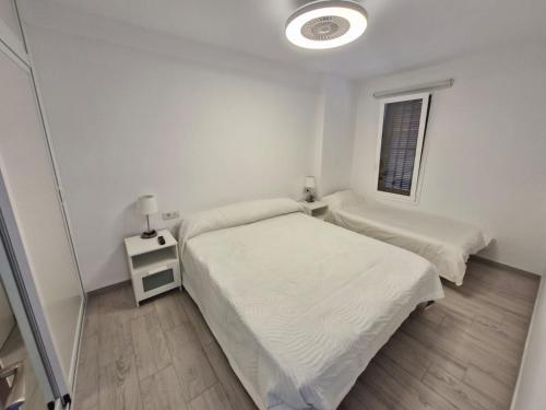 ein weißes Schlafzimmer mit zwei Betten und einem Fenster in der Unterkunft ¡Tal y como Hawaii! in Playa Fañabe