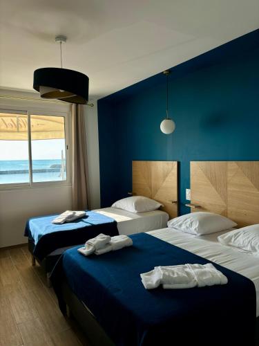 deux lits dans une chambre aux murs bleus dans l'établissement L'Hôtel De La Plage, au Grau-du-Roi