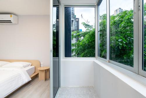 a bedroom with white walls and large windows at Wash House Chatuchak in Bangkok