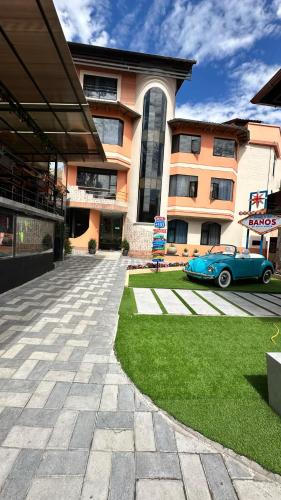 a blue car parked in front of a building at Hotel Tungurahua in Baños