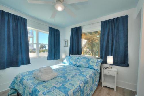 Schlafzimmer mit blauen Vorhängen, einem Bett und einem Fenster in der Unterkunft Fishy Fishy Down in Oak Island