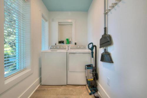eine weiße Waschküche mit einer Waschmaschine und einem Fenster in der Unterkunft Fishy Fishy Down in Oak Island