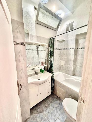une salle de bain avec un lavabo, une baignoire et des toilettes dans l'établissement Menton: superbe appartement, à Menton
