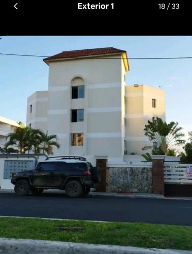 a black truck parked in front of a white building at Estancia Nana apartamento vista al mar piscina WIFI cocina completa aire acondicionado Lavadora secadora in Juan Dolio