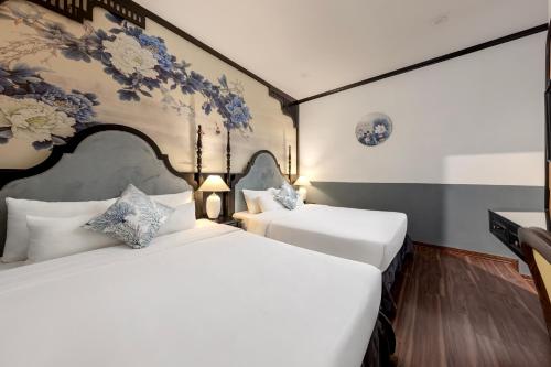 two beds in a room with a wall with flowers at Hanoi Elpis Hotel & Spa in Hanoi