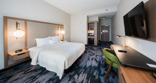 a hotel room with a bed and a desk and a tv at Fairfield Inn & Suites by Marriott Melbourne Viera Town Center in Melbourne