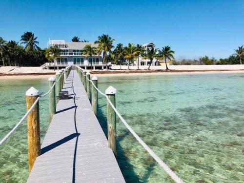 a wooden pier leading to a beach with a house at Palms Resort Main House - Key West in Sugarloaf Shores