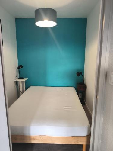 una cama en una habitación con una pared azul en Charmant studio, en Le Tholy