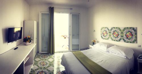 a bedroom with a bed and a tv and a window at Hotel Villa Pina Antico Francischiello in Massa Lubrense