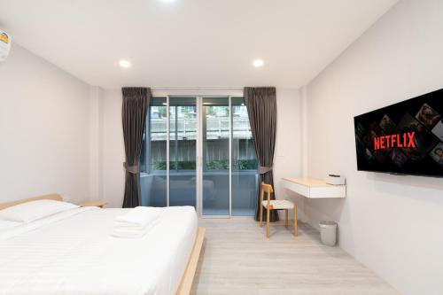 a bedroom with a bed and a desk and a tv at Wash House Chatuchak in Bangkok