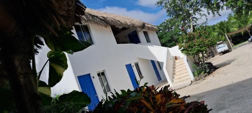 a white house with blue doors and a thatched roof at Hotel Posada Mykonos in Bacalar