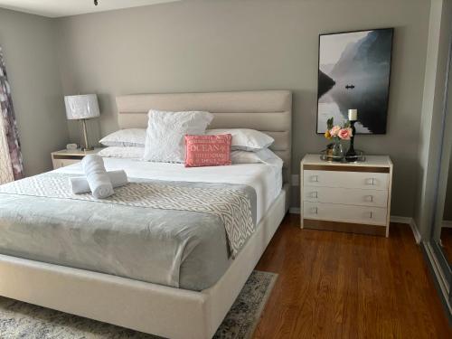 a bedroom with a white bed and a nightstand with two lamps at Bright & Cozy 4BR Home for Your Family Stay With Optional Pool Access in Mississauga
