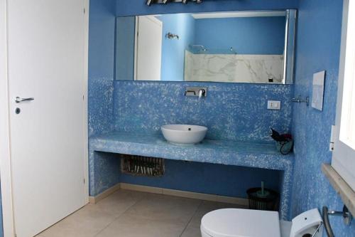 Un baño azul con lavabo e inodoro. en Villa Luxury fronte mare, en San Vito lo Capo