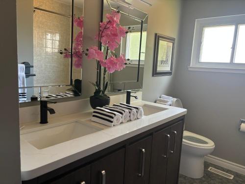 a bathroom with a sink and a vase with pink flowers at Bright & Cozy 4BR Home for Your Family Stay With Optional Pool Access in Mississauga