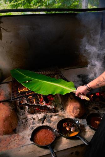 a person holding a large green umbrella over a grill at Hidden Valley Wilderness Lodge in San Ignacio