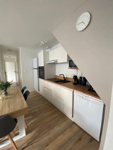 une cuisine avec des placards blancs et une horloge murale dans l'établissement Les Pics du Courtat, à Luchon