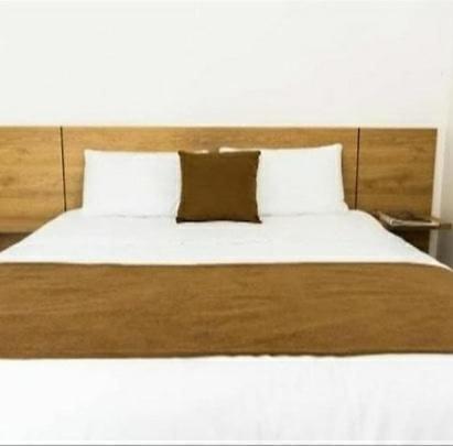 a bed with white sheets and a brown pillow at Hotel la quinta campestre in Villavicencio