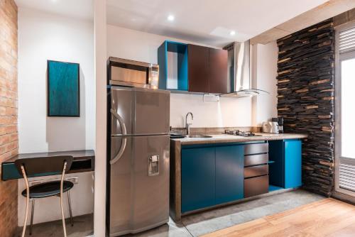 a kitchen with blue cabinets and a stainless steel refrigerator at Hotel 5 Elementos Corferias by HBP in Bogotá