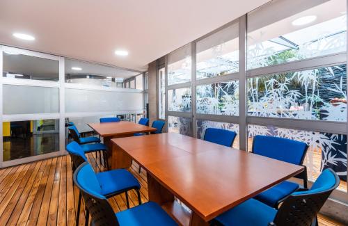 a conference room with wooden tables and blue chairs at Hotel 5 Elementos Corferias by HBP in Bogotá