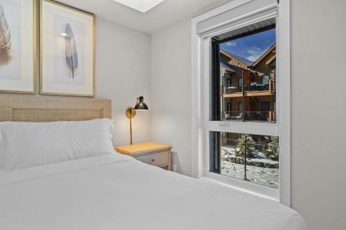 a bedroom with a white bed and a window at Pool and hot tub Stunning 2Bd haven in the Rockies in Dead Man's Flats