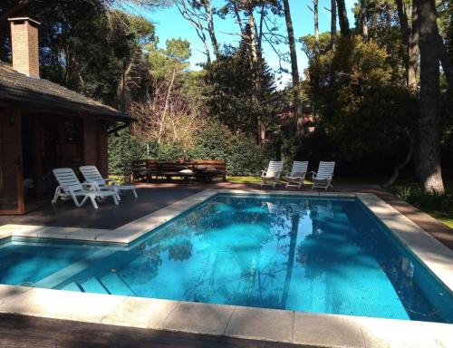 einen Pool mit Stühlen, einem Tisch und einem Haus in der Unterkunft Casa para 16 personas in Carilo