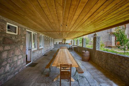 a patio with a wooden table and chairs under a wooden ceiling at Hotel Nini in Stepantsminda