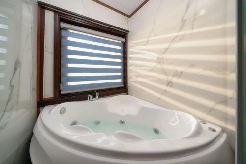 Una bañera blanca en un baño con ventana. en Renea Boutique Cruise, en Ha Long