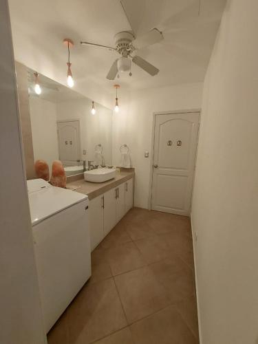 a white kitchen with two sinks and a ceiling fan at VillaLore piscina exclusiva BBQ AC max 11 personas 5min playas in Carpintero