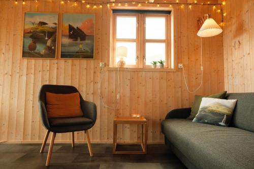 a living room with a couch and a chair at Múlafossur Cottages by famous waterfall in Gásadalur in Gásadalur