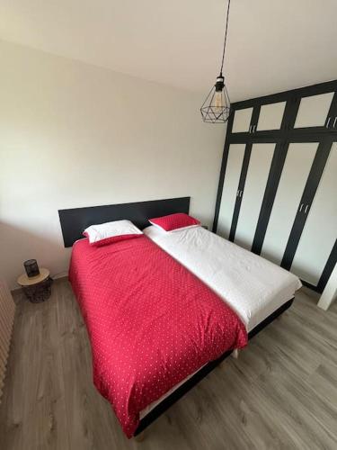 une chambre avec un grand lit avec une couverture rouge dans l'établissement Gîte du tétras, à Gérardmer