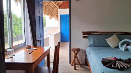una camera da letto con una scrivania, un letto e un tavolo di Hotel Posada Mykonos a Bacalar