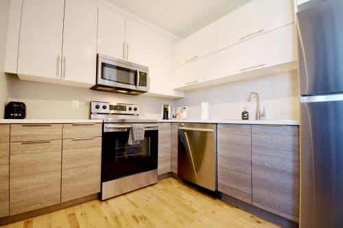 a kitchen with white cabinets and stainless steel appliances at Capitol Robinson by Bower Boutique Hotels in Moncton