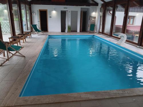 a large swimming pool with blue water and chairs at Dida Joja in Lički Osik