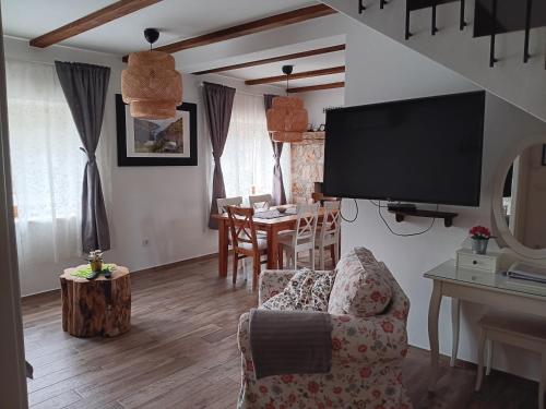 a living room with a tv and a chair and a table at Dida Joja in Lički Osik