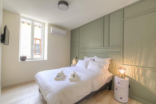 una camera da letto con un grande letto bianco con scarpe di La suite Guillaume, T2 cosy contemporain a Vienne