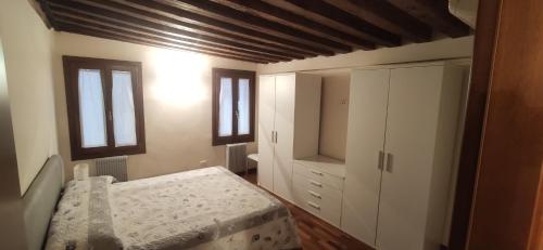 1 dormitorio con 1 cama, armario y ventanas en CA' Botteri, en Venecia
