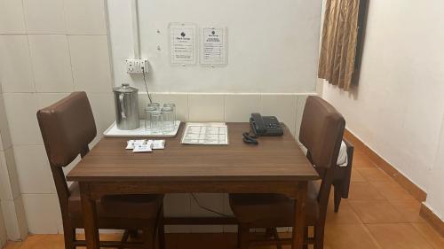 a wooden table with chairs and a telephone on it at Hotel Saluja in Siliguri