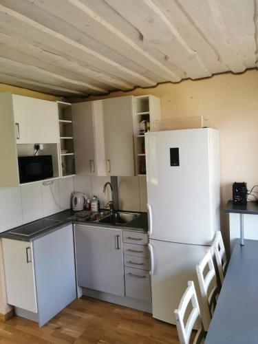 a kitchen with a white refrigerator and a table at Līdumnieki in Vērgale