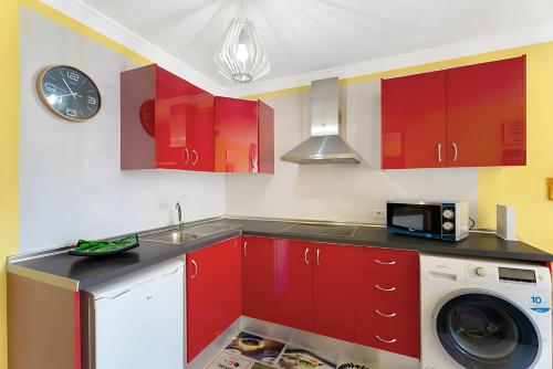 eine Küche mit roten Schränken und einer Waschmaschine in der Unterkunft Apartamento en Calle Heraclio Sánchez in La Laguna