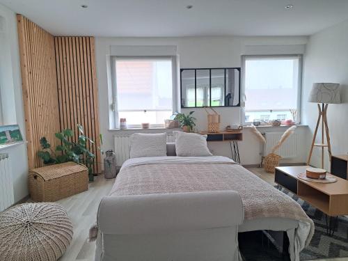 a bedroom with a large bed and two windows at le refuge du bonheur in Bitche