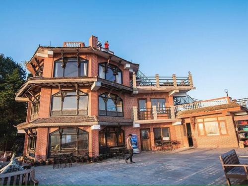 a large brick building with people on top of it at Peaceful Cottage & Cafe Du Mont in Nagarkot