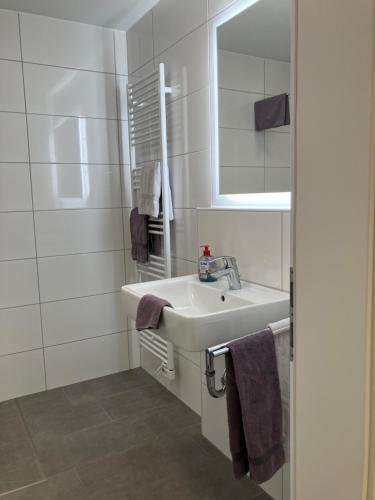 ein weißes Badezimmer mit Waschbecken und Spiegel in der Unterkunft Haus Etzold in Norderney